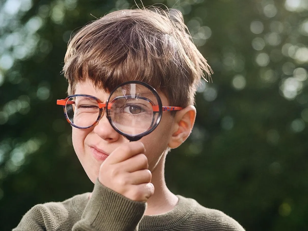 Bambino miope che osserva con lente di ingrandimento
